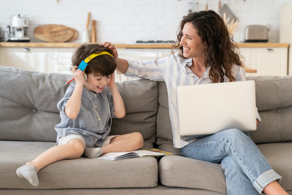 woman smiling touch little boy's head that is listening to headphones - side hustles jobs for stay at home moms