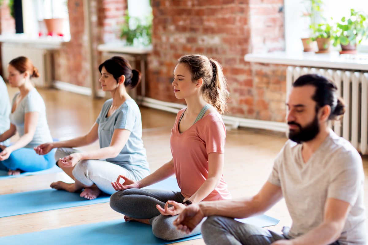 group of people making yoga exercises at studio fitness, yoga and healthy lifestyle concept - group of people meditating in lotus pose at studio