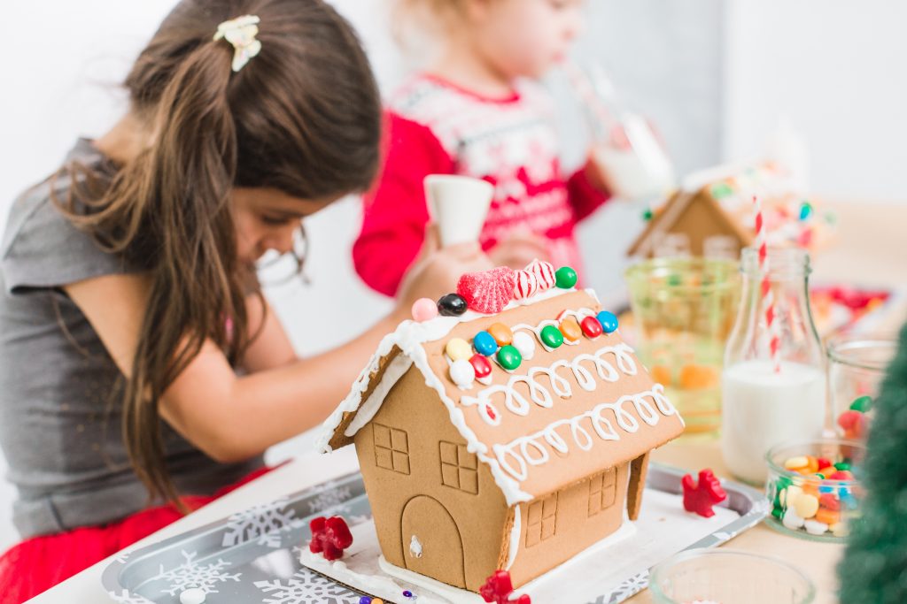 Kids decorating small gingerbread houses at the Christmas craft party.