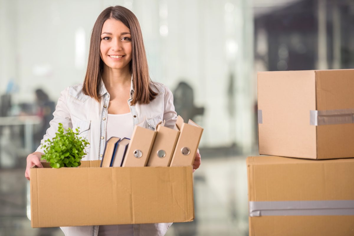 Young woman holding box with things in office.