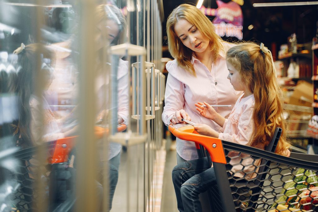 Mother and daughter in supermarket cart looking over shopping list