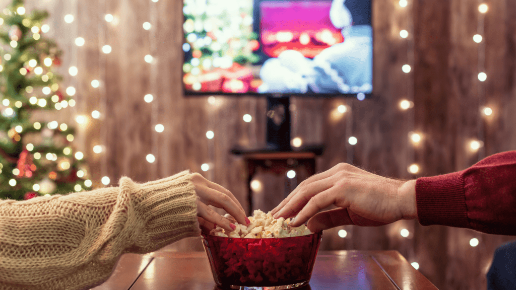 hands grabbing popcorn in front of TV during Christmas time
