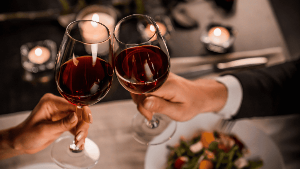 Couple holding glass of wine over a meal