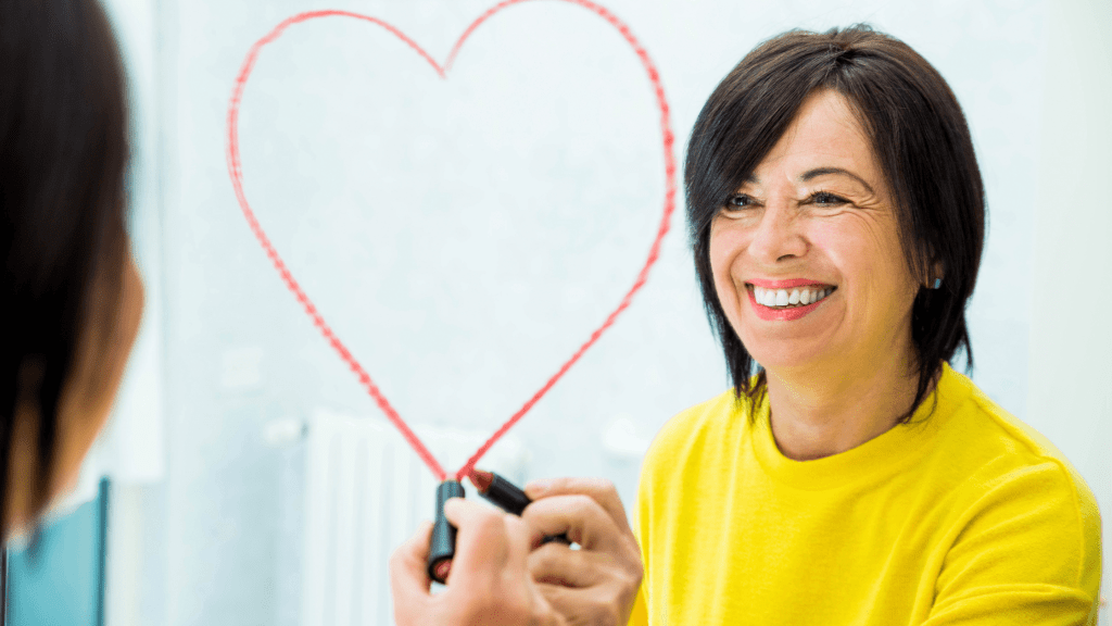 woman smiling drawing heart with lipstick on mirror
