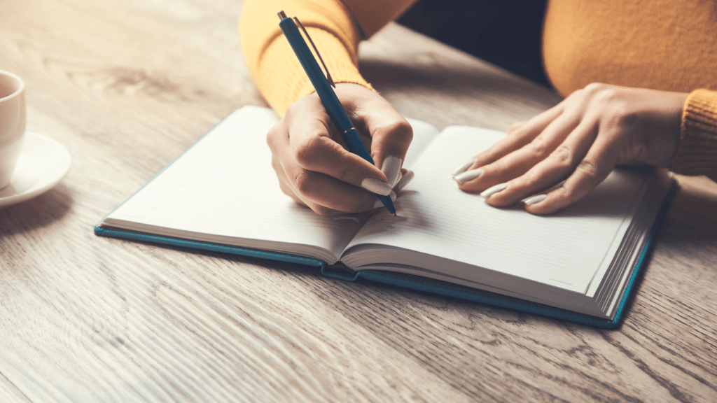 person holding pen over a notebook